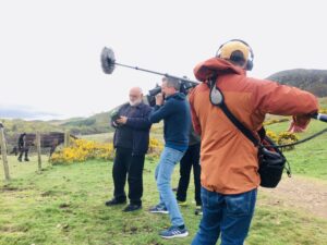 Alexei Sayle standing on the hill at Swanston Farm being filmed by film crew from Oxford Films in 2022